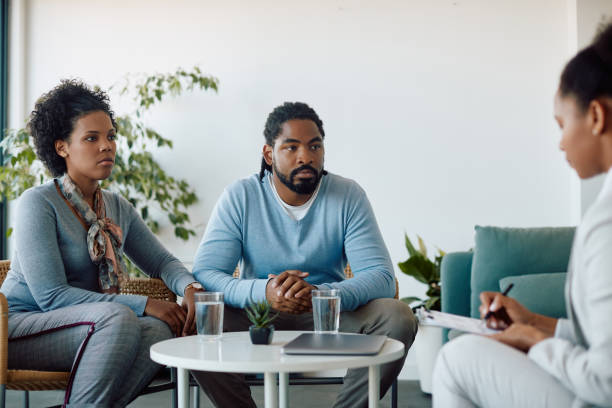 istock Black couple holding hands while talking to financial advisor in the office. 1407260442