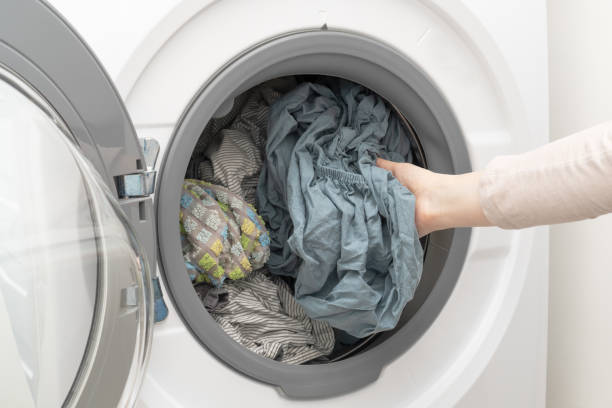 istock Clean wet laundry inside of washing machine. Woman's hand pulling out washed clothes from the drum. 1407264466