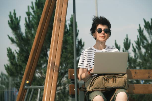 istock Woman is using laptop outdoors 1407265007
