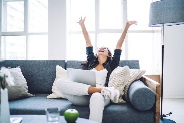istock Emotional prosperous female blogger satisfied with successful project completing sitting with laptop computer, happy cheerful woman enjoying good news from social networks raising hands celebrating 1407265620