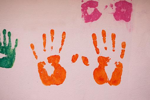 Orange coloured handprints on a pink wall