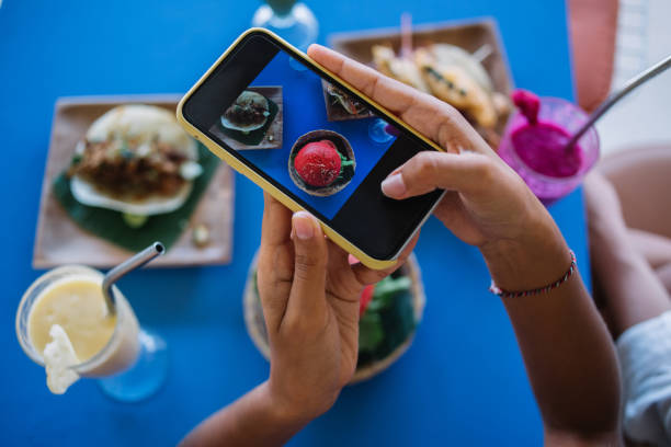 istock Cropped female vlogger using cellphone main camera for clicking media pictures and creating content for sharing to food blog, gourmet photographing Mexican cuisine during lunch in Latin bistro cafe 1407270541