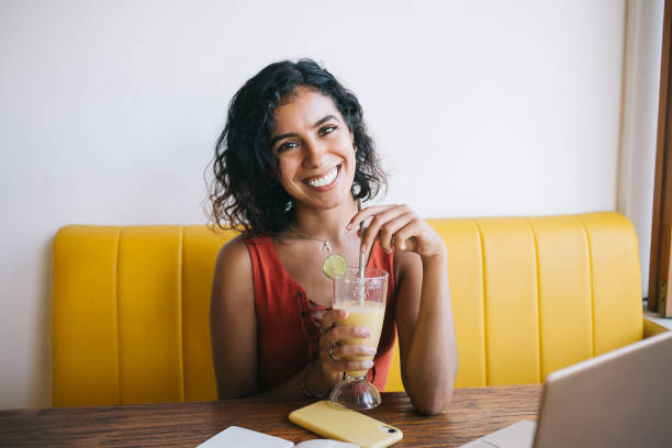 portrait of cheerful it professional with sincerely smile laughing at camera during remote working in cafe with good internet connection, successful female freelancer posing at table with netbook - blueberry smoothie milk shake drink imagens e fotografias de stock