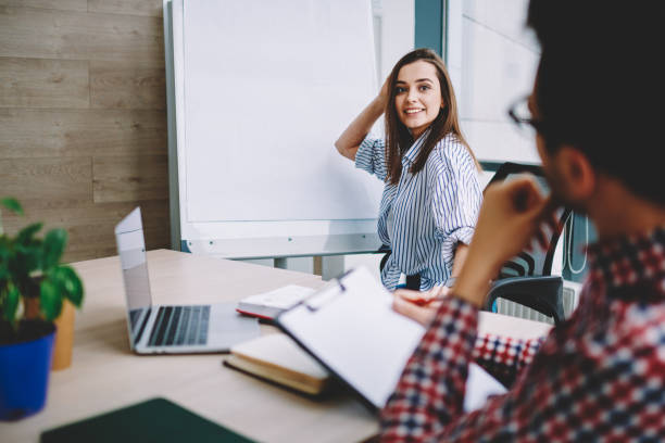 istock Successful female trainee smiling during occupation interview with man using mockup flip chart with copy space area for business information, colleagues collaborating on startup ideas in office 1407272395