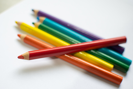 Various colored pencils on top of a white sheet with copyspace