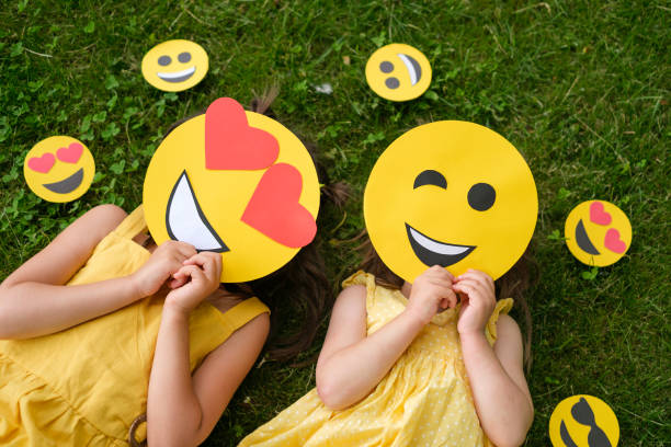 istock Two people with different cardboard smiles cover their faces lying on the grass. Lover and winking emoticons, top view 1407273213