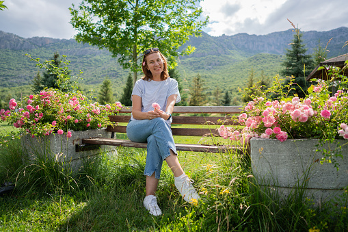 Portrait of modern, attractive mature woman sitting in the natural park