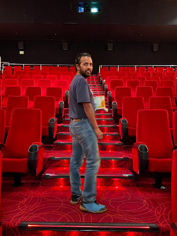 Stock photo showing close-up view of man climbing steps to find seat in cinema.
