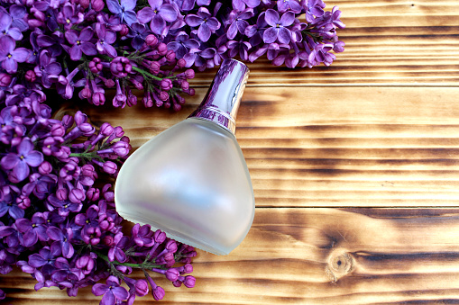 Yana wooden background lies lilac in a glass bottle of perfume.