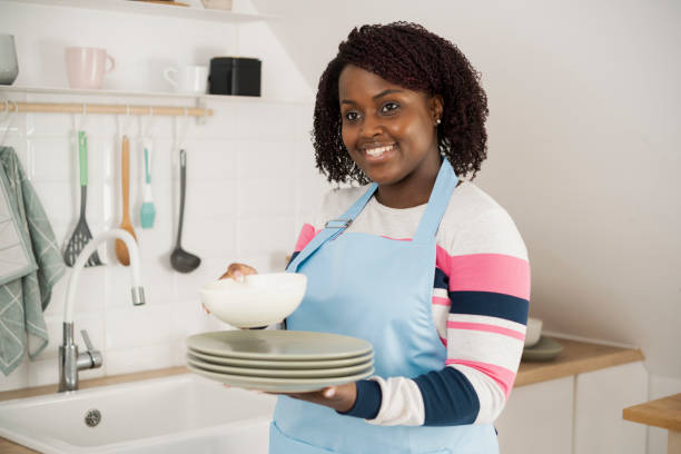 istock Happy Afro woman arranging washed plates at her kitchen 1407276343