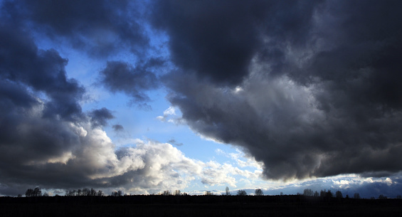 Dark heavy clouds obscure the sky at sunset. Spring bad weather in the foothills of the Western Urals.