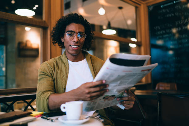 istock Cheerful man with newspaper sitting at table in cafe 1407277188