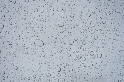 Drops of water on the window glass after rain. Gray wet textured background