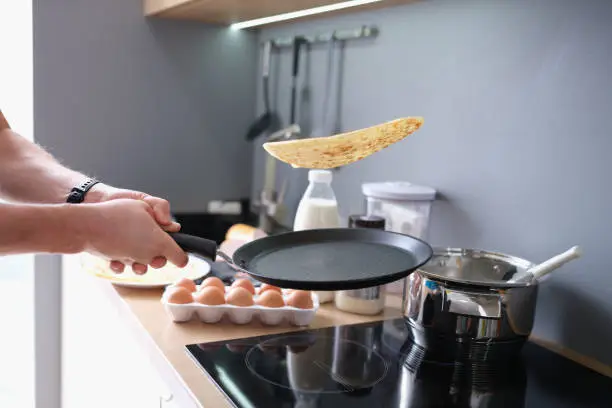 Person deftly flips the pancakes in pan. Cooking delicious pancakes at home