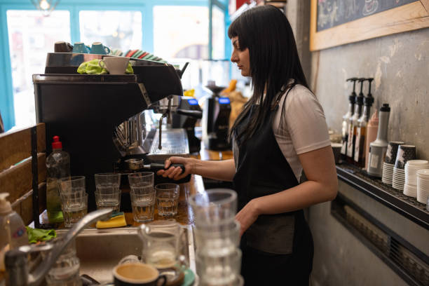 istock Female barista making coffee while using espresso maker, at the coffee shop 1407277732