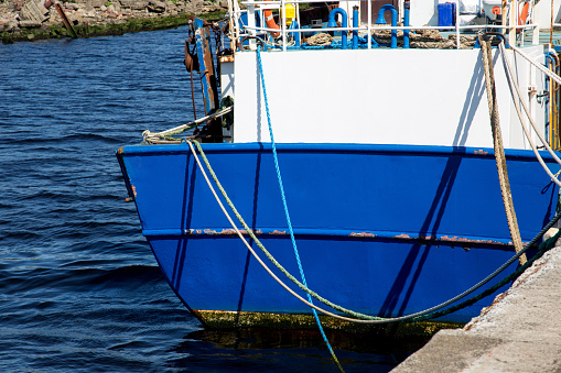 Blue painted fishing vessel stern view at a harbour location