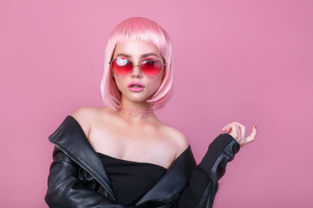 Stylish portrait of woman in sunglasses with bright colored pink hair and pink make-up in sunglasses stock photo