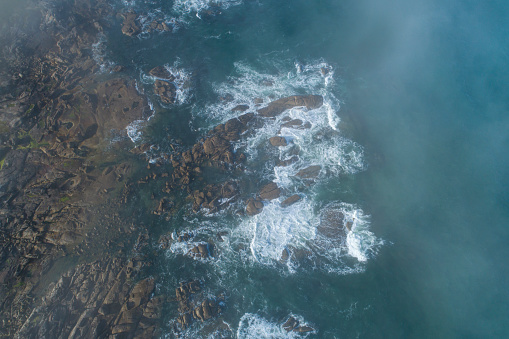zenithal aerial view of some waves on the rocky shore