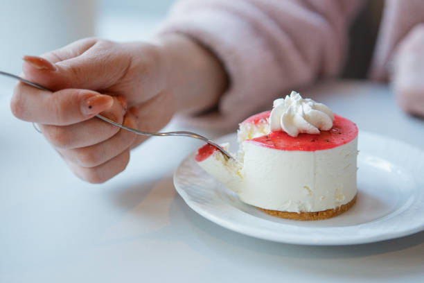 istock Red and white cake being cut with fork in female hand. 1407281708