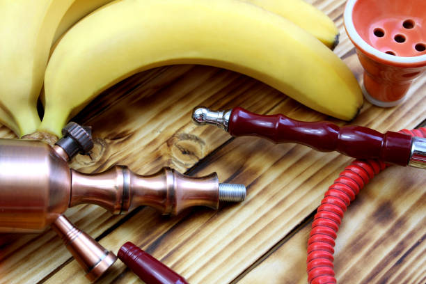 Details of a hookah with fruits lie on a wooden table.