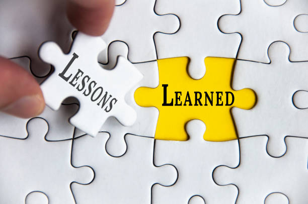 istock Lessons learned text on Jigsaw Puzzle with one hand holding a missing jigsaw pieces. Improvement concept 1407283868