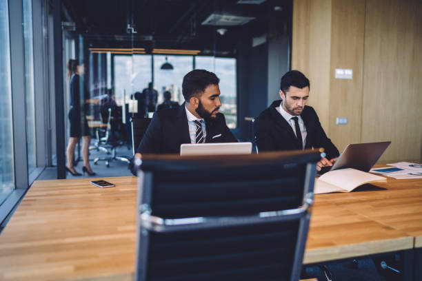 istock Multiethnic colleagues in formal wear working on laptops in office 1407284145