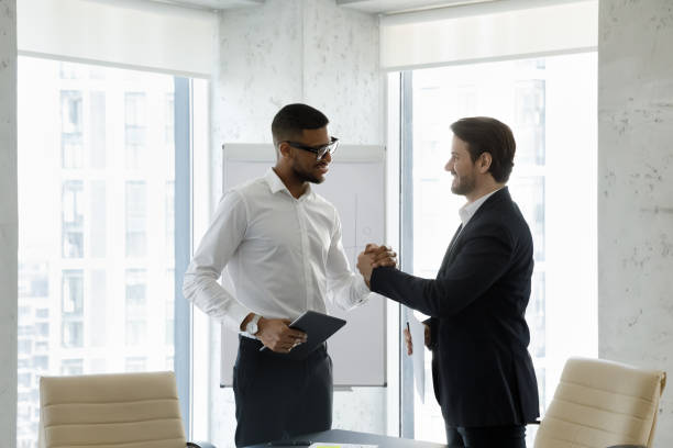 istock Two millennial multi racial businessmen shake hands express respect 1407284264