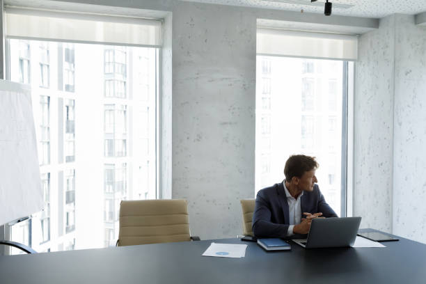 istock Successful businessman staring out window seated at modern skyscraper office 1407285173