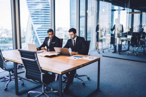 istock Male company employees using laptop computer for research useful information on financial platform for business people, skilled executive managers collaborating on web project discussing ideas at desk 1407285379