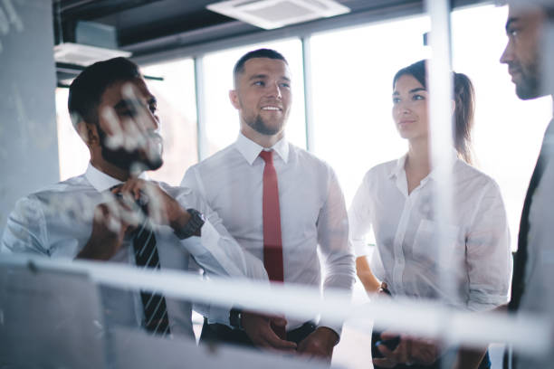 istock Group of multiracial employees standing behind glass wall and discussing work in modern office 1407285409