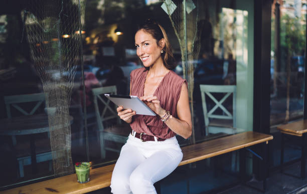 istock Confident middle age woman browsing tablet in modern cafe 1407286008