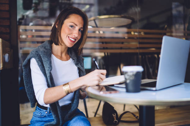 istock Cheerful woman writing notes in cafe 1407286037
