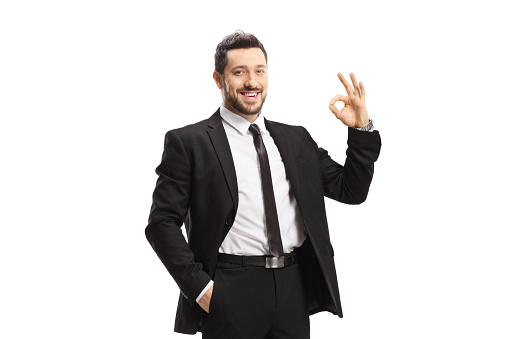 Young man wearing black suit and gesturing ok sign isolated on white background