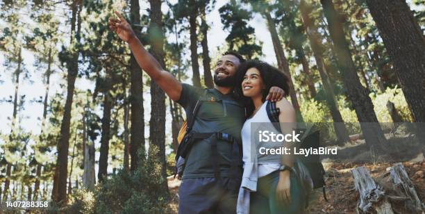 Happy Couple Hiking A Trail And Enjoying The View In A Forest Cheerful Adventurous Man And Woman Pointing At Scenery While Taking A Break From Exploring Their Surroundings During A Trek In Nature Stock Photo - Download Image Now