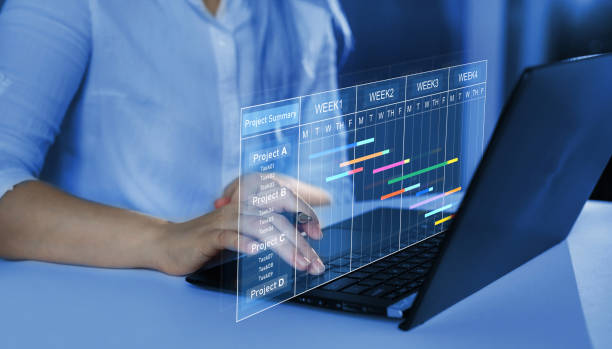 istock Business Project Management System.Project manager working on laptop and updating tasks and milestones progress planning with Gantt chart scheduling interface for company on virtual screen. 1407290447