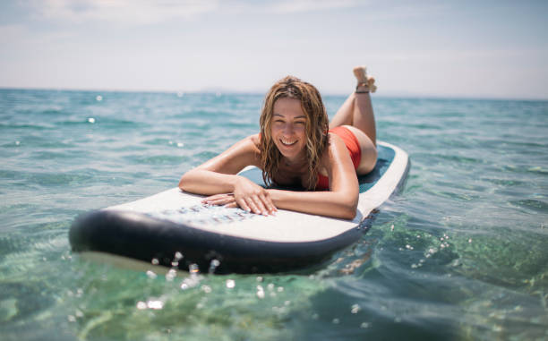 istock Smiling woman enjoys sunbathing on paddle board 1407290472