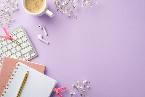 Business concept. Top view photo of workplace keyboard cup of frothy coffee open planner gold pen clips earbuds and white gypsophila flowers on isolated lilac background with copyspace