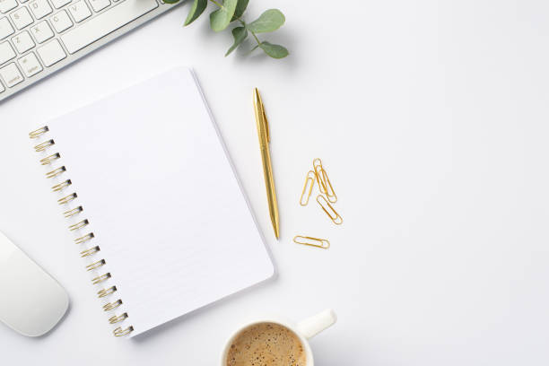 istock Business concept. Top view photo of workstation white keyboard computer mouse open notebook cup of coffee clips gold pen and eucalyptus sprig on isolated white background 1407292253