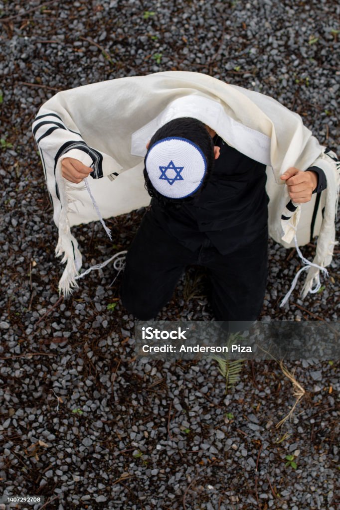 Vertical photo of Jew with kippah raising his tallit with his hands covering his back. Vertical photo of Jew with kippah raising his tallit with his hands covering his back and face tilted downward. Hasidism Stock Photo