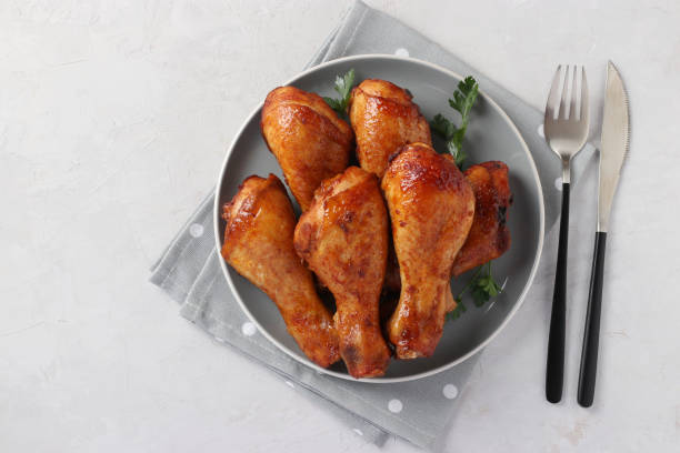Roasted chicken drumsticks in honey and soy sauce on grey plate, top view. stock photo