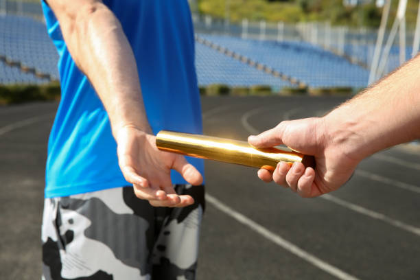 istock Man passing baton to his partner at stadium, closeup 1407299523