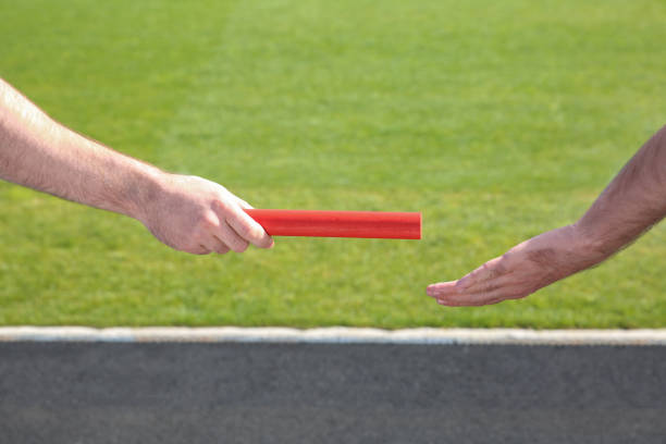 istock Man passing baton to his partner at stadium, closeup 1407299525
