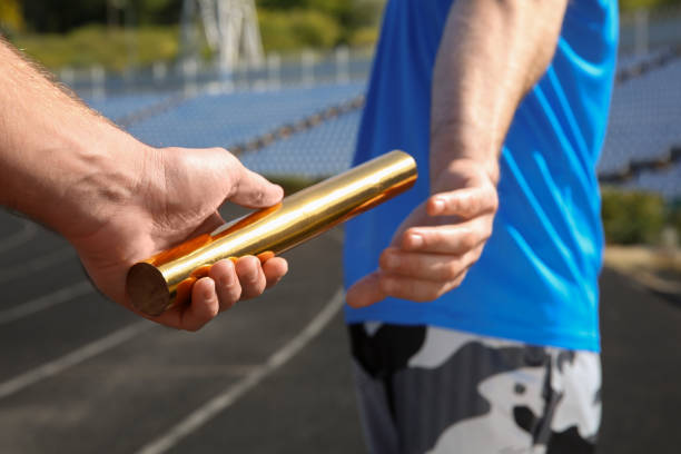istock Man passing baton to his partner at stadium, closeup 1407299559