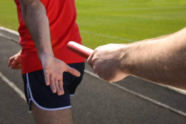 istock Man passing baton to his partner at stadium, closeup 1407299563