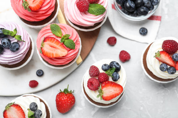 istock Sweet cupcakes with fresh berries on light marble table, flat lay. 1407301176