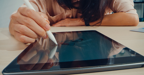 Close up of hand young Asian woman writing digital tablet while working in office. Business people concept.