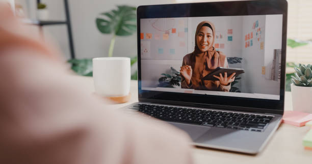 gros plan d’une jeune femme asiatique utilisant un ordinateur portable passant un appel vidéo avec un client tout en travaillant au bureau. - colleague looking at camera indoors lifestyles photos et images de collection