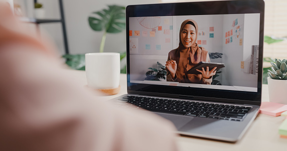 Close up of young Asian woman using laptop making video call with customer while working in office. Business people concept.