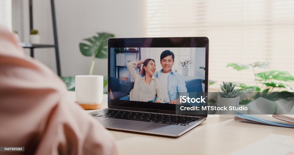 Close up of young Asian woman using laptop making video call with friends while working in office. Close up of young Asian woman using laptop making video call with friends while working in office. Business people concept. Connection Stock Photo
