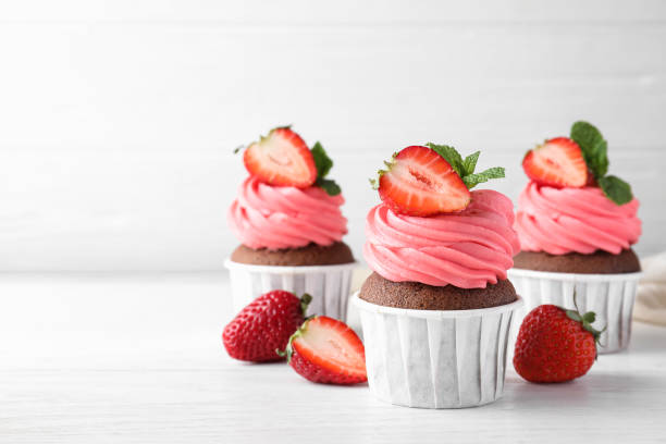 istock Sweet cupcakes with fresh strawberries on white table. Space for text 1407301780